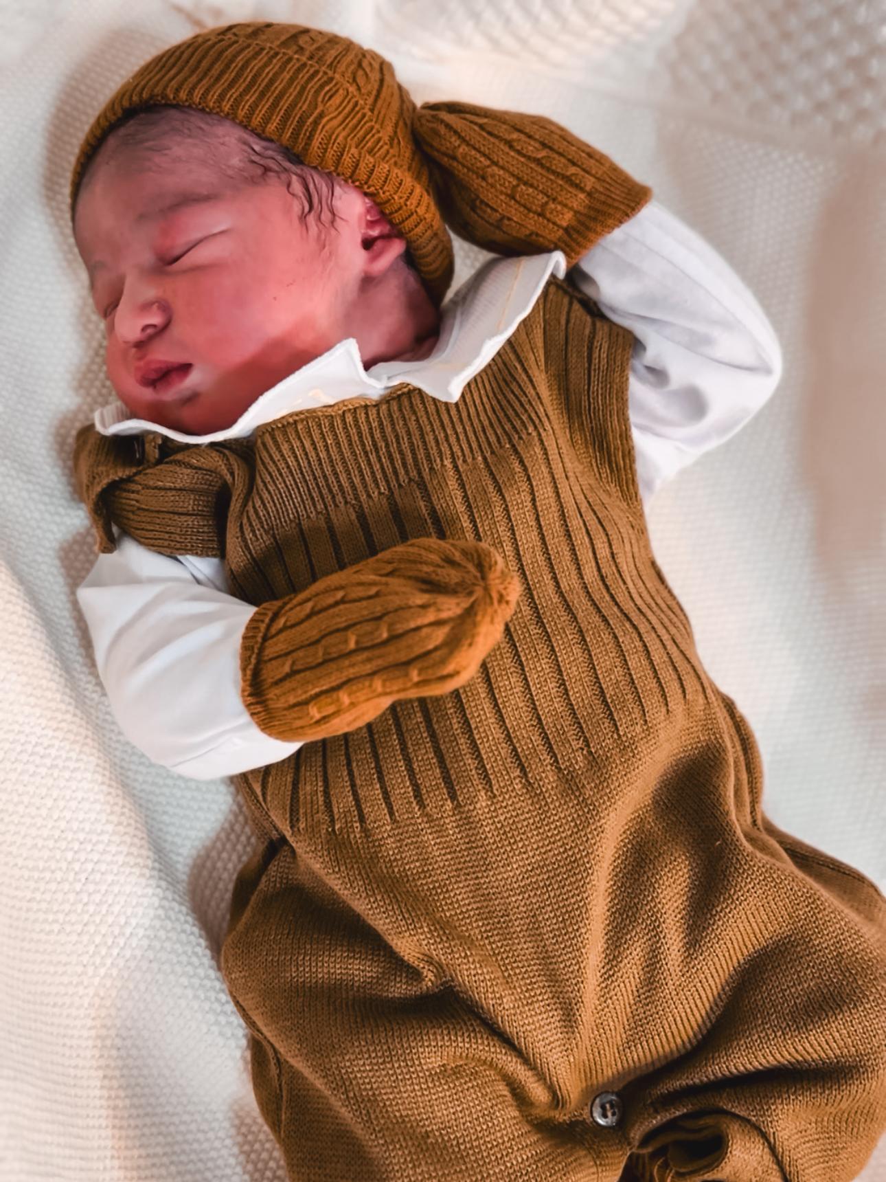 Foto de um recem nascido com roupa marrom